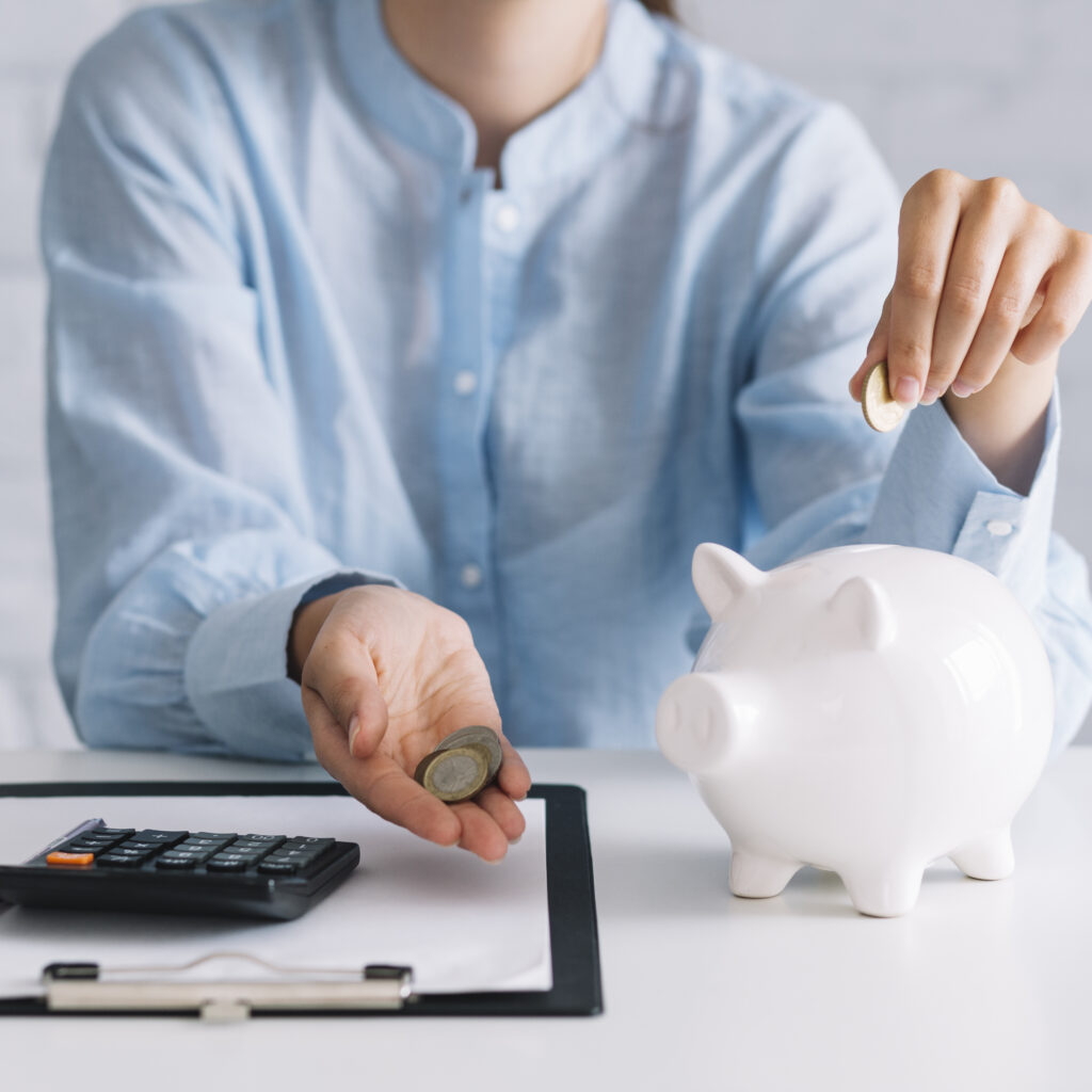 businesswoman-showing-coins-with-white-piggybank-desk