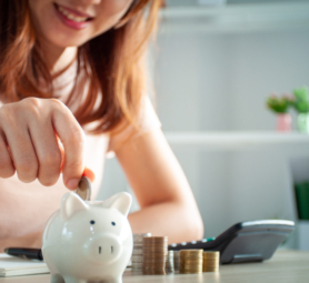 Happy Asian women put money in a piggy bank. save money concept
