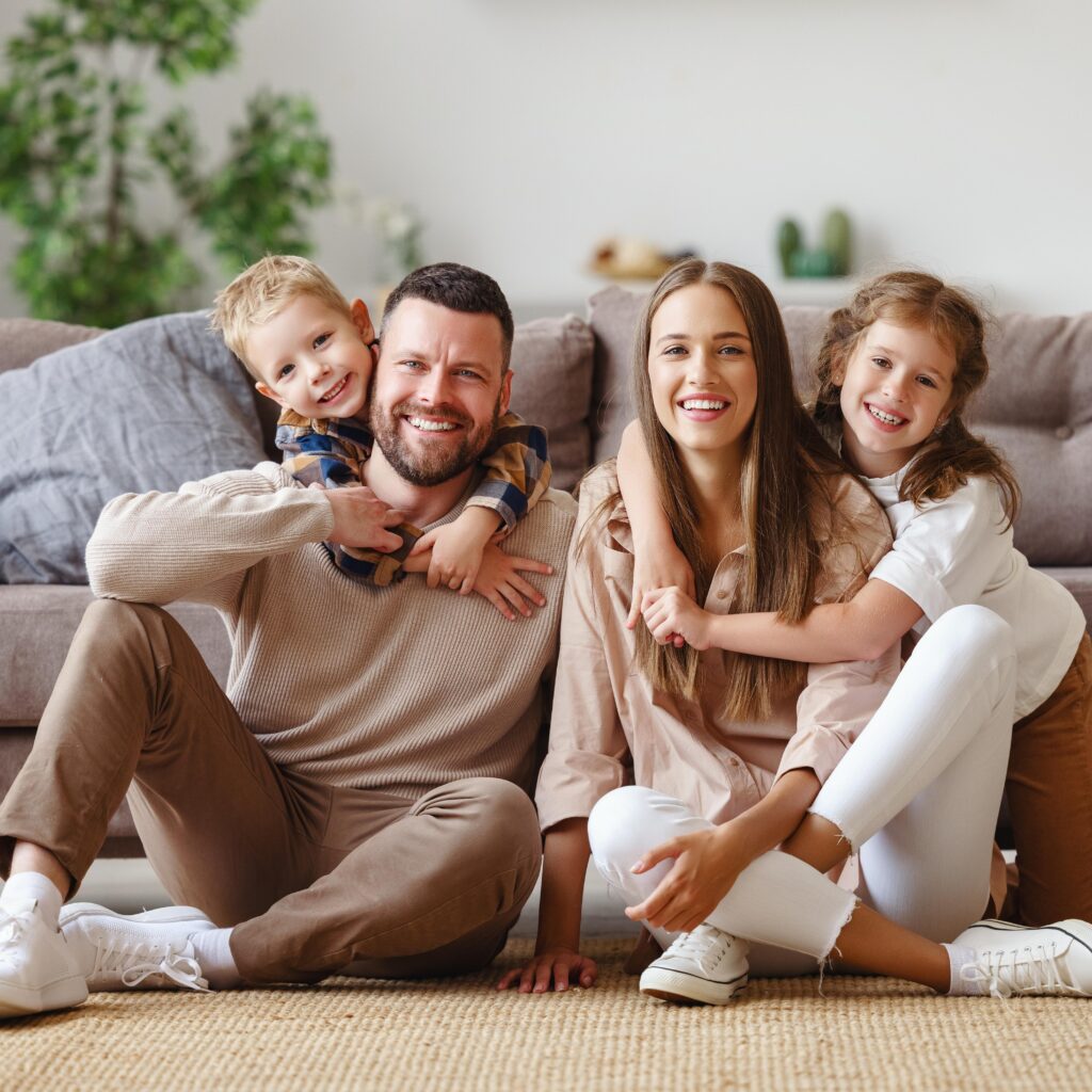 happy family mother father and children at home on the couch