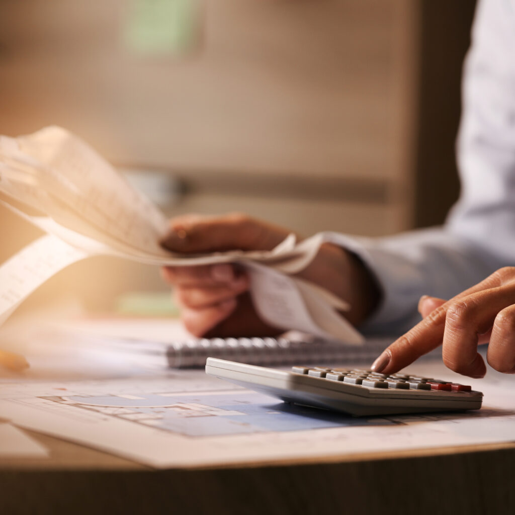 Close-up of economist using calculator while going through bills and taxes in the office.